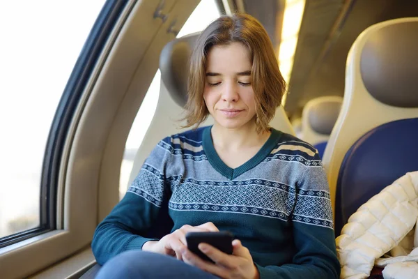 Portret van een mooi meisje die communiceren via de telefoon in de auto van een trein. Mobiele communicatie - de vreugde van de mededeling van overal — Stockfoto