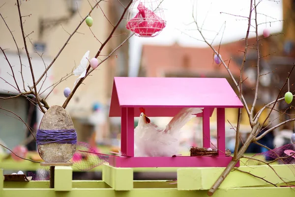 Easter decorations on the street of small town in France. Easter painted eggs hanging on a branch of tree and chicken toy as decoration. — Stock Photo, Image