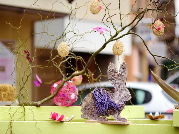 Easter decorations on the street of small town in France. Easter eggs hanging on a branch of tree and wooden bunny toys as decoration. — Stock Photo, Image