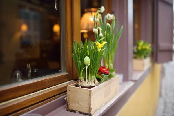 Gezellige venster van een houten huis versierd met bloemen en houten ornamenten voor Pasen. — Stockfoto