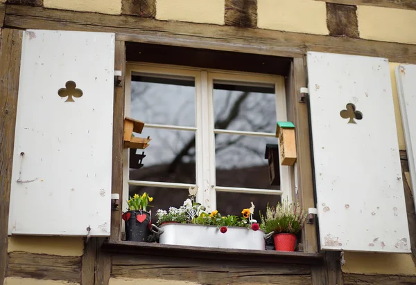 Gezellige venster van een houten huis versierd met bloemen en houten ornamenten voor Pasen. — Stockfoto