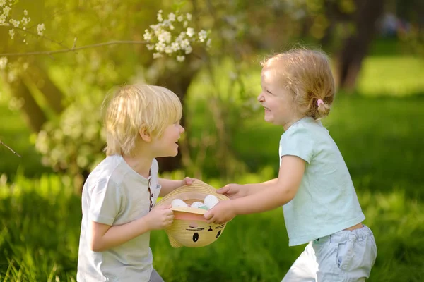 Affascinanti bambini piccoli a caccia di uova dipinte nel parco primaverile il giorno di Pasqua . — Foto Stock