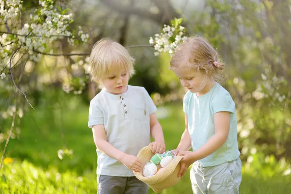 Очаровательные маленькие дети охотятся за покрашенными яйцами в весеннем парке на Пасху . — стоковое фото