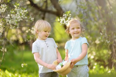Sevimli küçük çocuklar Paskalya gününde bahar parkında boyalı yumurta için avlar.