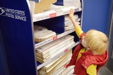 New York, ABD - 23 Ekim 2018: Postanedeki küçük çocuk bir paket - zarf / posta kutusu seçiyor.