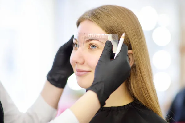 Kosmetikerin, die Augenbrauen entwirft. attraktive Frau bekommt Gesichtspflege im Schönheitssalon. Architektur-Augenbrauen. — Stockfoto