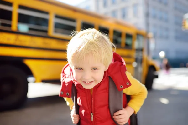 Elève avec cartable avec autobus scolaire jaune sur fond . — Photo