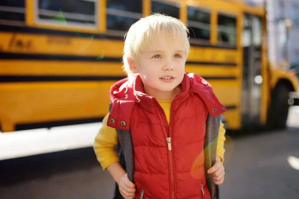 Elève avec cartable avec autobus scolaire jaune sur fond . — Photo