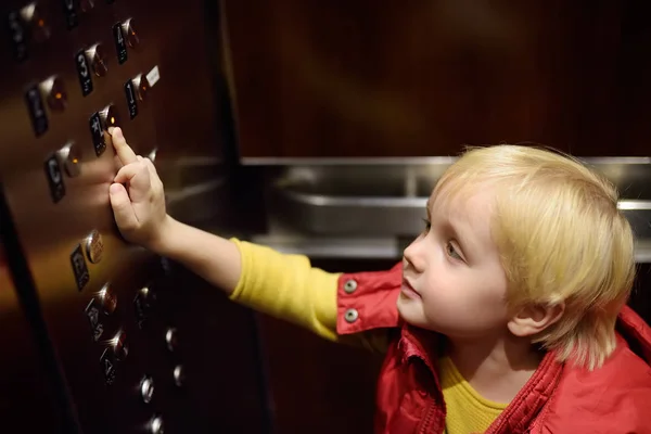 Lttle boy pressing button of lobby in elevator — Stock Photo, Image