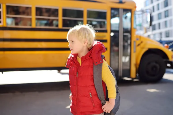 Elève avec cartable avec autobus scolaire jaune sur fond . — Photo