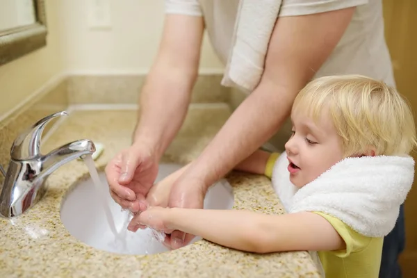 El niño y su padre lavándose las manos con jabón en el baño juntos. Higiene para niños pequeños . —  Fotos de Stock