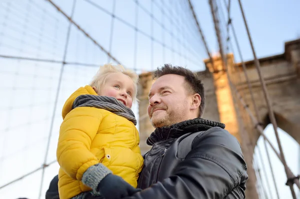 Schattige kleine jongen en zijn vader op Brooklyn Bridge met wolkenkrabbers op achtergrond — Stockfoto