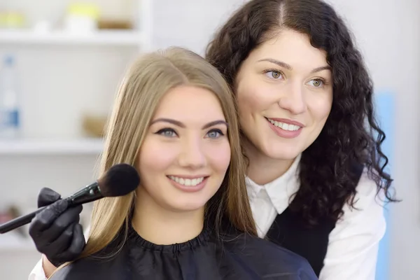 Maquilleur appliquant le ton de la fondation à l'aide d'un pinceau spécial sur le visage jeune beau modèle. Soins du visage et maquillage — Photo