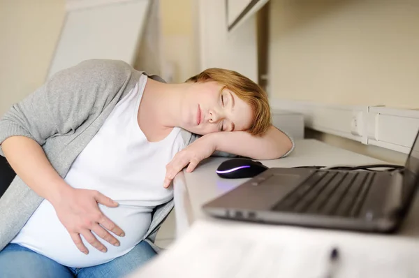 Mulher grávida cansada dormindo perto do laptop em seu local de trabalho no escritório. Seguro médico para engravidar. Licença de maternidade. Gravidez e trabalho . — Fotografia de Stock