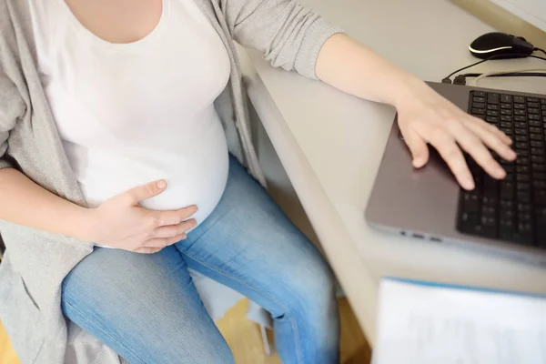 Ofisteki iş yerinde dizüstü bilgisayar üzerinde çalışan hamile bir kadın. Sağlık sigortası çocuk doğurma. Doğum izni. Gebelik ve iş. — Stok fotoğraf