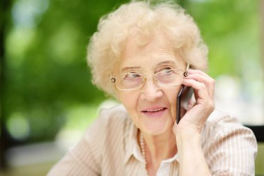 Kıvırcık beyaz saçlı, telefonda konuşan güzel yaşlı bir bayan. İletişim, konuşma, dedikodu. Yaşlı bayan yaşam tarzları.