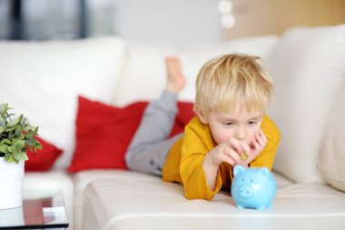 Küçük çocuk kumbara içine sikke koyarak.