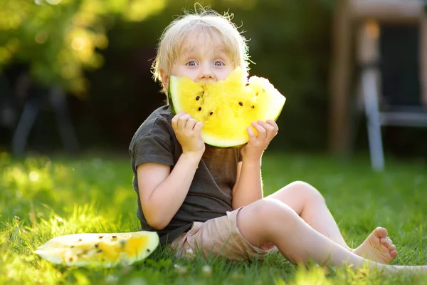 Sarı karpuz açık havada yemek sarı saçlı sevimli kafkas küçük çocuk. — Stok fotoğraf