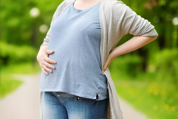 Portret van een mooie zwangere jonge vrouw in het Spring Park — Stockfoto