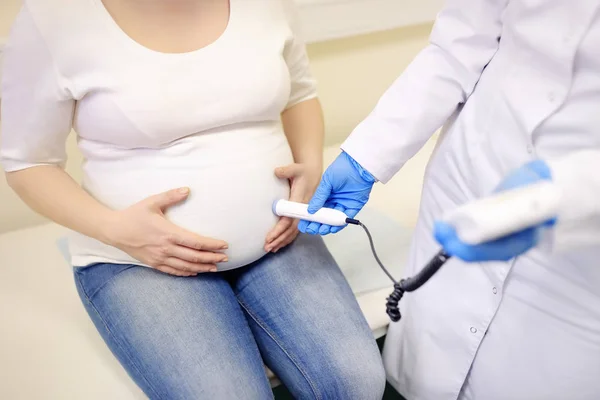 Médico usando dispositivo droppler fetal para ouvir batimento cardíaco do bebê na clínica. Seguro médico para engravidar. Médico de família para a gestação. Licença de maternidade . — Fotografia de Stock