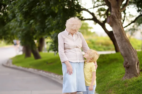 Vacker farmor och hennes lilla barnbarn går tillsammans i parken. — Stockfoto