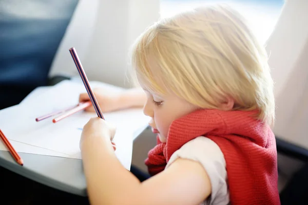 Joyful little boy sitting by aircraft window during the flight