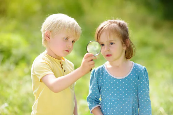 Kinderen verkennen de natuur met vergrootglas. Close-up. Kleine jongen en meisje op zoek met Vergrootglas — Stockfoto