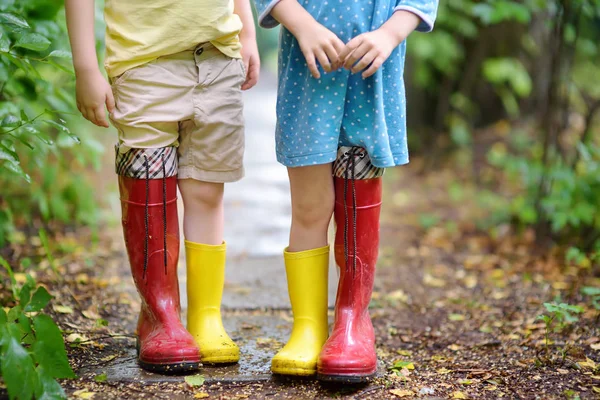 Little children wearing oversized rubber boots holding hands. Brother and sister playing together. — Stock Photo, Image