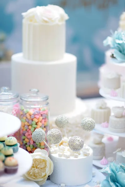 Traditionelle mehrschichtige Hochzeitstorte, die mit Blumen geschmückt ist. und schöne süße Nachspeise - Cupcakes, Marshmallow, Chupa-Chups. — Stockfoto