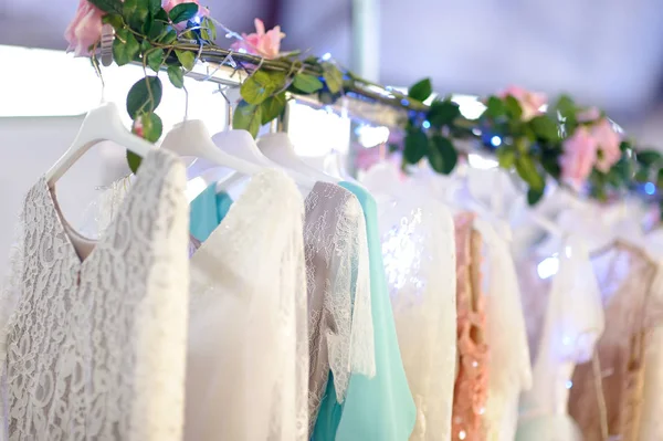 Câteva rochii elegante de mireasă, domnișoară de onoare, seară, rochie de minge sau bal pe un cuier într-un magazin de mireasă . — Fotografie, imagine de stoc