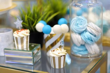 Yıldönümü / düğün lezzetli tatlı tatlı mavi ve beyaz tonları - cupcakes, marshmallow, vanilyalı kek açılır. Şık tatlı masa.