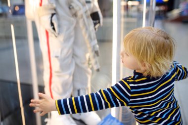 Müzede astronot uzay kıyafeti arayan küçük beyaz çocuk