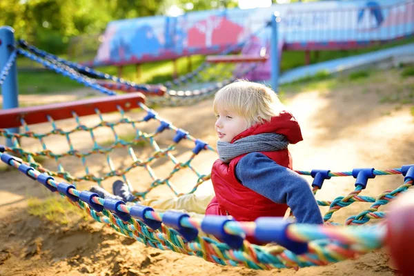 Mignon petit garçon caucasien blond qui s'amuse sur une aire de jeux extérieure. Loisirs sportifs actifs pour enfants. Enfant sur hamac — Photo