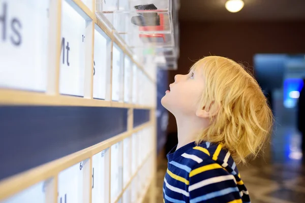 Little? aucasian chico está buscando una exposición en un museo científico. Tabla periódica de elementos químicos . —  Fotos de Stock