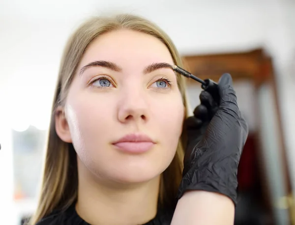 美容师梳眉使用特殊刷子在脸上年轻漂亮的模型。面部护理和化妆 — 图库照片