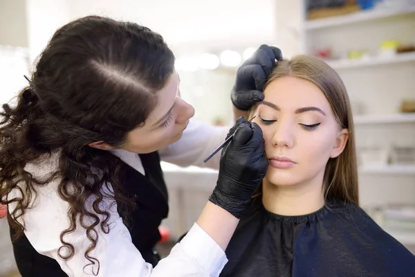 美容师用刷子画眼纤丽。有吸引力的女人在美容院获得面部护理和化妆。建筑眉毛. — 图库照片