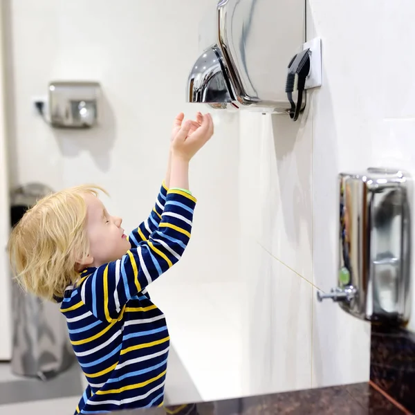 Kleiner kaukasischer Junge trocknet seine Hände in einer Toilette — Stockfoto