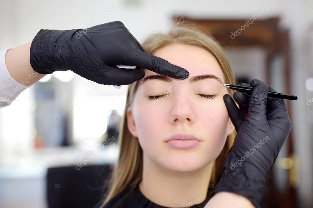 Cosmetologist eyebrow plucking. Attractive woman getting facial care and makeup at beauty salon. Architecture eyebrows.