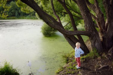 Göletin kıyısında duran üzgün ya da gücenmiş küçük çocuk. Çocuk kendini kaybet. Çocuk kaçıyor. Evden kaçış.