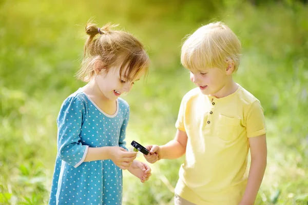 Enfants explorant la nature avec une loupe. Ferme là. Petit garçon et fille regardant avec loupe sur camomille . — Photo