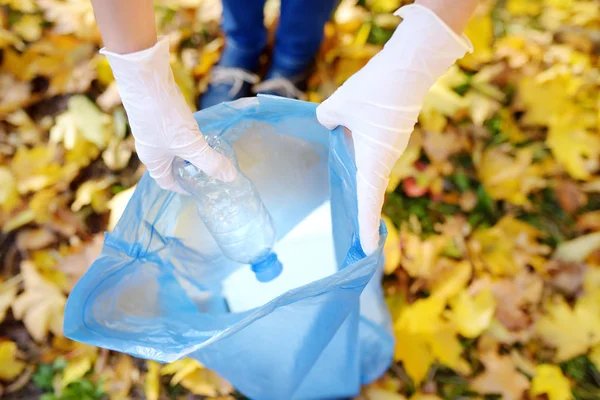 Wolontariusz zbierając plastikowe śmieci i umieszczając go w biodegradowalny worek na zewnątrz. — Zdjęcie stockowe