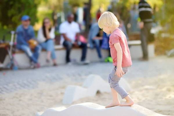 Bambino che si diverte nel parco giochi all'aperto del parco pubblico nella soleggiata giornata estiva . — Foto Stock