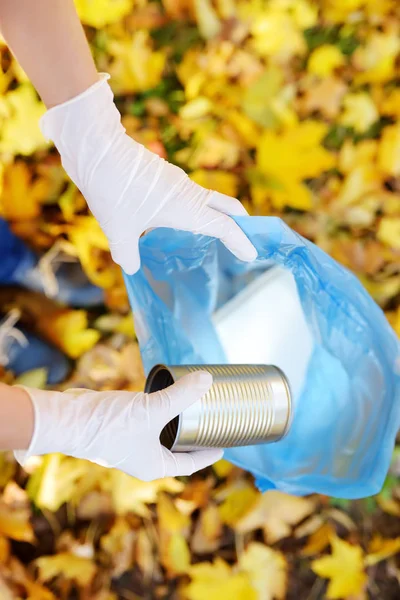 Wolontariusz zbierając metalowe śmieci i umieszczając go w biodegradowalnych woreczku na zewnątrz. — Zdjęcie stockowe