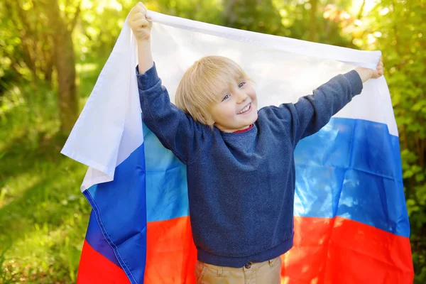 Портрет милого мальчика в общественном летнем парке с российским флагом на заднем плане. Болельщики поддерживают и болеют за свою сборную. День независимости . — стоковое фото