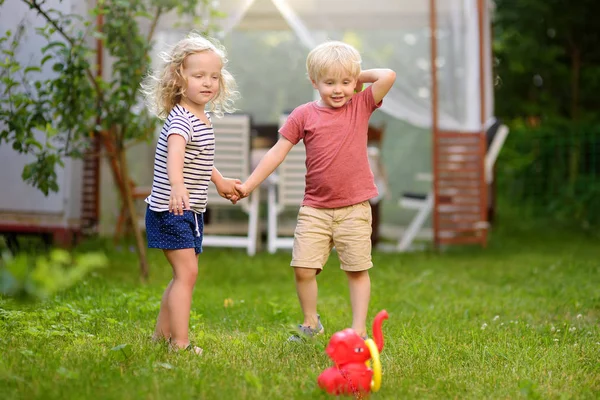 夏の屋外でリングを投げるゲームで遊ぶかわいい男の子と女の子. — ストック写真