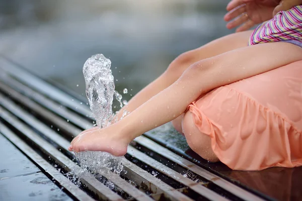 Fuß des kleinen behinderten Mädchens in den Armen seiner Mutter, die sich an einem sonnigen Sommertag im Springbrunnen des öffentlichen Parks vergnügt. Zerebrale Kinderlähmung. — Stockfoto