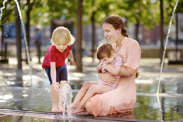 Mamma med funktionshindrade flicka och pojke ha kul på fontänen på Sunny Summer Park. Barn cerebral pares. Familj med handikappade barn. — Stockfoto