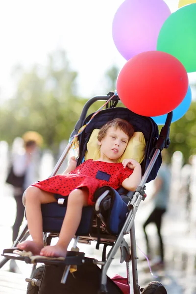 Carina bambina disabile in sedia a rotelle festeggiare il compleanno o passeggiare nel parco estivo. Paralisi cerebrale infantile. Inclusione . — Foto Stock