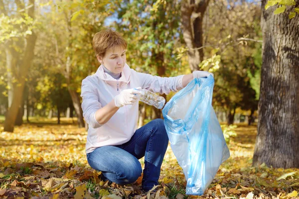 Wolontariusz zbierając plastikowe śmieci i umieszczając go w biodegradowalny worek na zewnątrz. — Zdjęcie stockowe