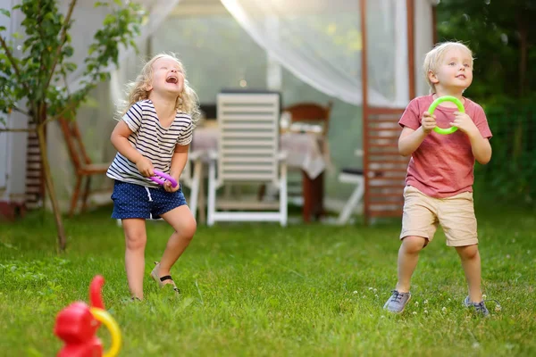 Mignon petit garçon et fille jouer dans le jeu jeter des anneaux à l'extérieur de l'été . — Photo